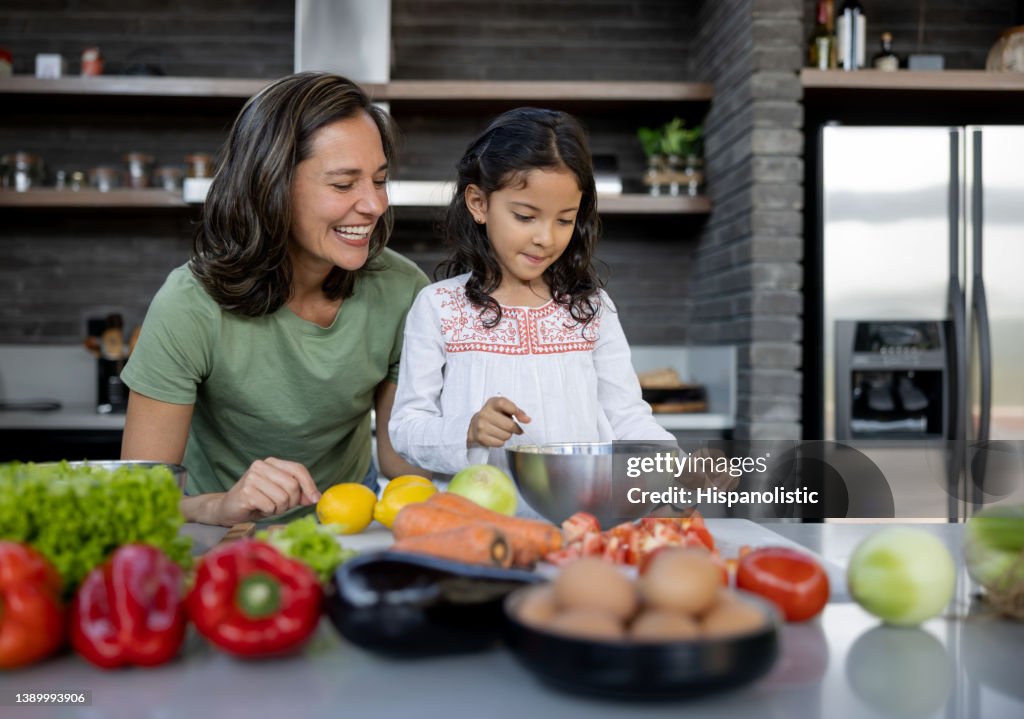 Happy mother and daughter cooking dinner together at home
