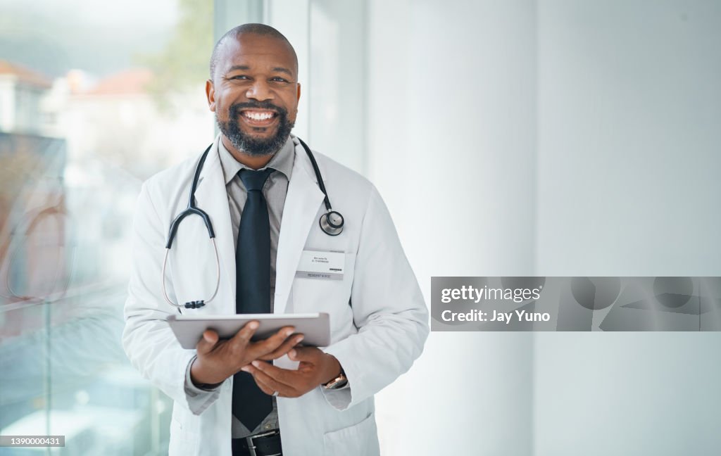 Aufnahme eines reifen Arztes mit einem digitalen Tablet in einem modernen Krankenhaus