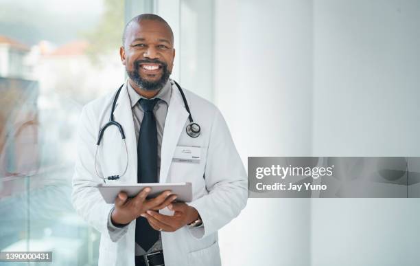 shot of a mature doctor using a digital tablet in a modern hospital - manspersoner bildbanksfoton och bilder