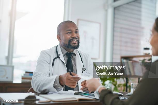 scatto di un medico maturo che ha una consultazione con il suo paziente - notepad white table foto e immagini stock