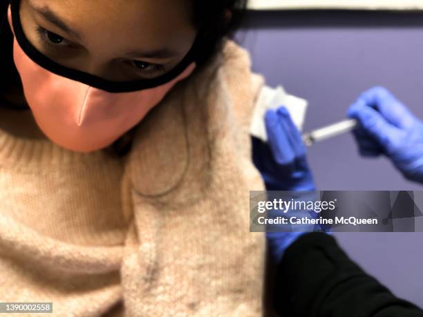 ouch: young mixed-race female receives a vaccination shot in the arm from a medical worker - spanish flu nurse stock pictures, royalty-free photos & images