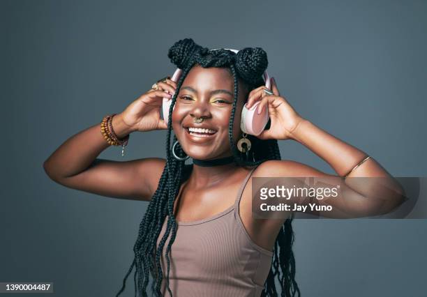 studio shot of a trendy young woman using headphones against a grey background - lady grey background stock pictures, royalty-free photos & images