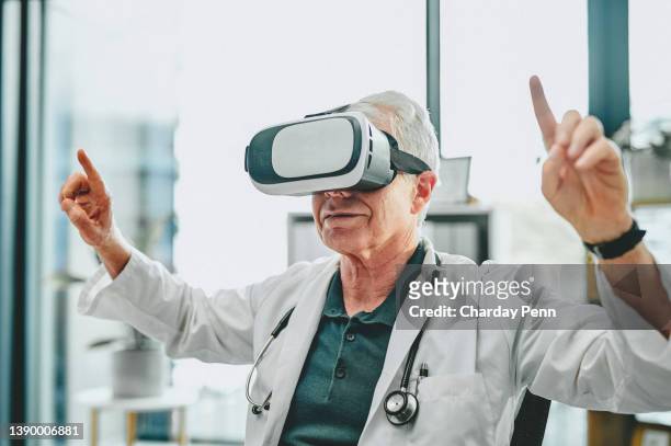 photo d’un médecin senior utilisant un casque de réalité virtuelle dans un hôpital moderne - lunettes de pilote de course photos et images de collection