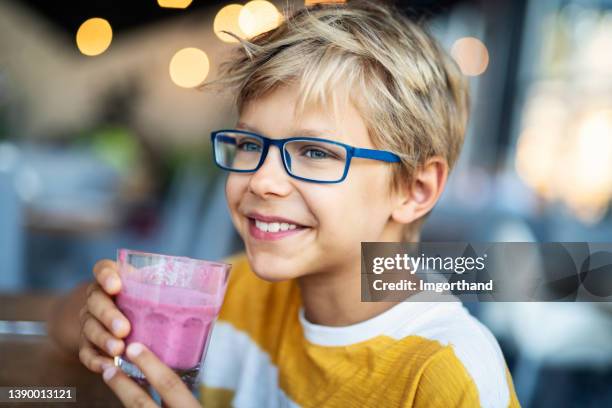 新鮮なヨーグルトスムージーのグラスを楽しむ小さな男の子の肖像画。 - blended drink ストックフォトと画像