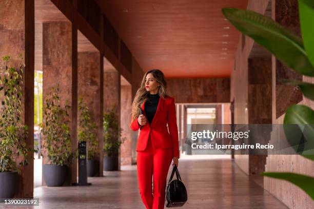 young caucasian businesswoman in a red suit arriving at a hotel, business trip - star style lounge imagens e fotografias de stock