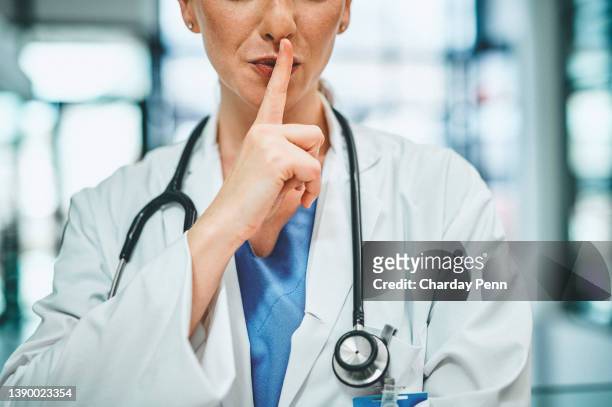 shot of a doctor with her finger on her lips in a modern hospital - finger on lips bildbanksfoton och bilder