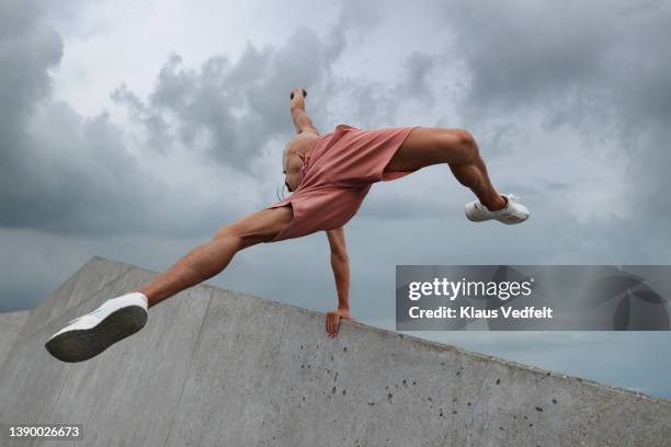 young shirtless male dancer jumping over wall - gray shorts stock pictures, royalty-free photos & images