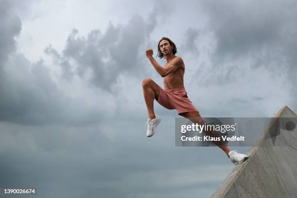 young shirtless male dancer jumping from wall - men shorts stock pictures, royalty-free photos & images