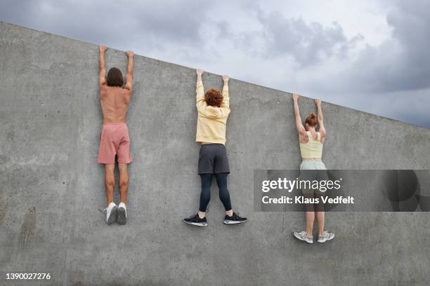 ballet dancers hanging together from gray wall - draped stockfoto's en -beelden