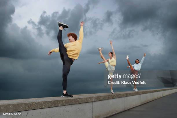dancers practicing ballet on gray wall against sky - spagat stock-fotos und bilder