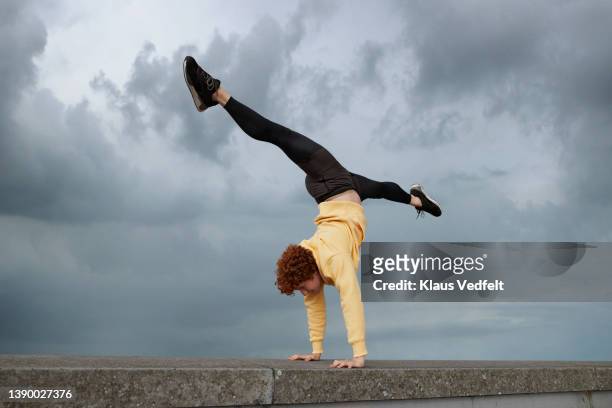 male ballet dancer practicing handstand on wall - split acrobatiek stockfoto's en -beelden