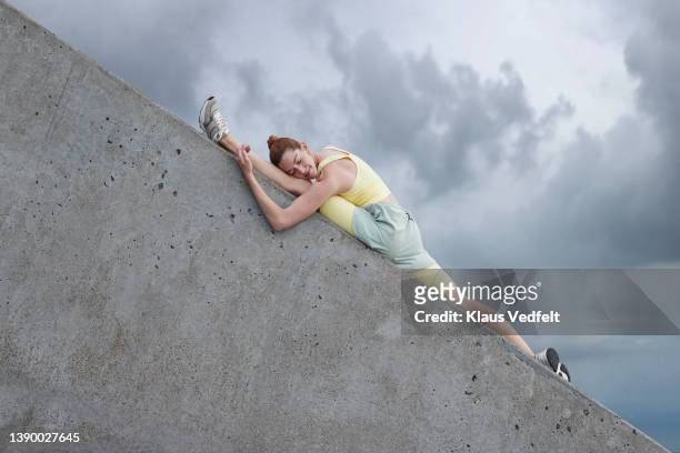 flexible ballerina doing splits on gray wall - öresundregion stock-fotos und bilder