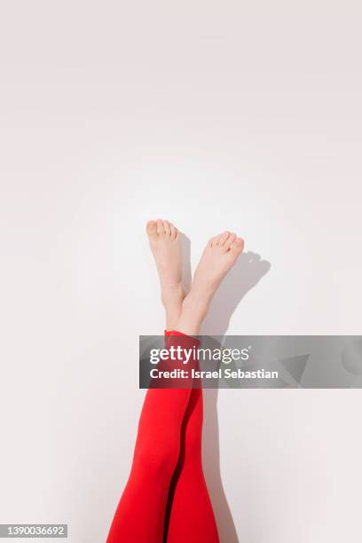 legs of crop unrecognizable barefoot female in red leggings against white background - piernas en el aire fotografías e imágenes de stock