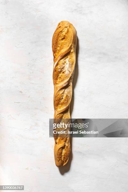 view from above of a delicious baguette on a white wooden background - flute stockfoto's en -beelden