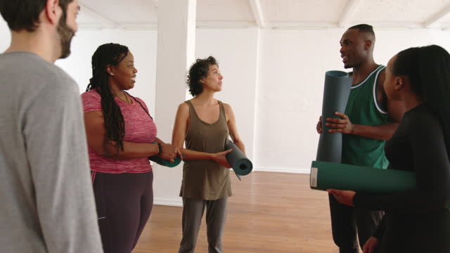 Group of people holding yoga mats talking after yoga class