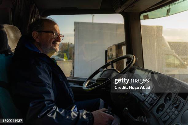 older truck driver inside the cab. - old truck stock-fotos und bilder