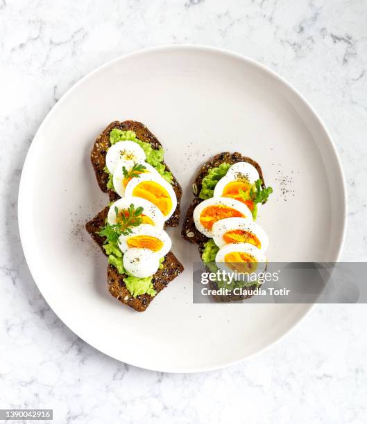 wholegrain crackers with avocado and boiled eggs on a plate on white background - crispbread stock pictures, royalty-free photos & images