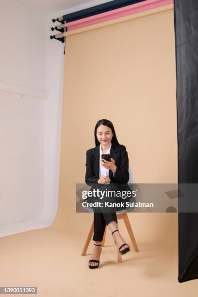 beautiful woman posing in studio - sitting and using smartphone studio stockfoto's en -beelden