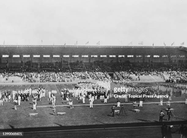 Spectators in the stands watch athletes from competing countries taking part in the Parade of Nations during the opening ceremony of the 1924 Summer...