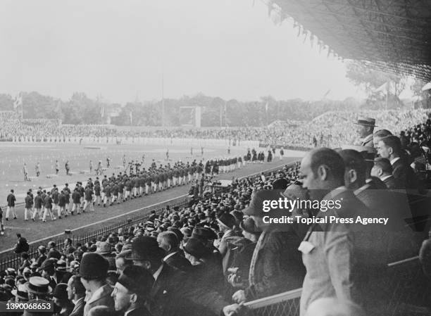 Spectators in the stands watch athletes from the Great Britain team take part in the Parade of Nations during the opening ceremony of the 1924 Summer...