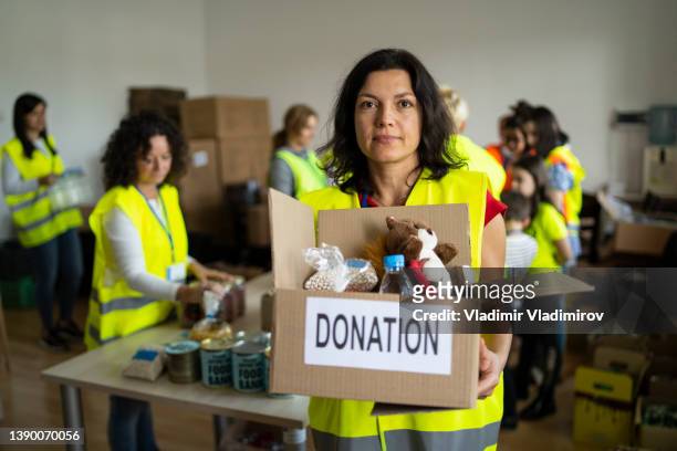 middle aged woman holding a box with food for donation - refugee camp imagens e fotografias de stock