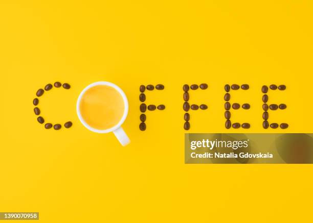 inscription from coffee beans with white cup on bright yellow background top view - yellow milk stock-fotos und bilder