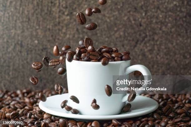 coffee beans falling into white cup. cafe drinkware on pile of arabica scented grains mockup - 平豆 ストックフォトと画像