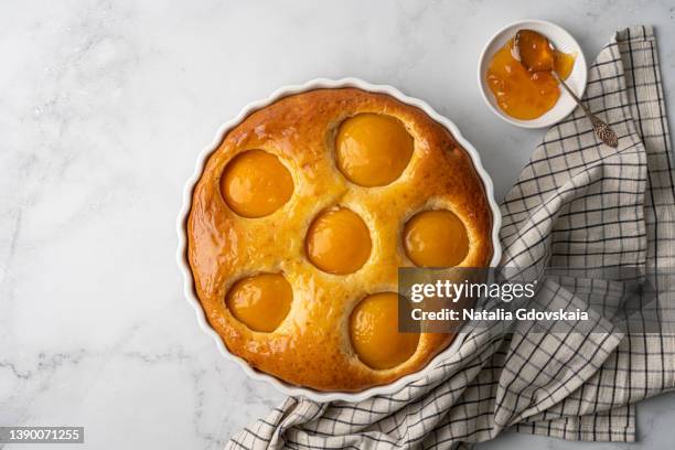 delicious baked sweet aprikot cake on white bright background served with saucer with peach syrup and napkin - damasco fruta - fotografias e filmes do acervo