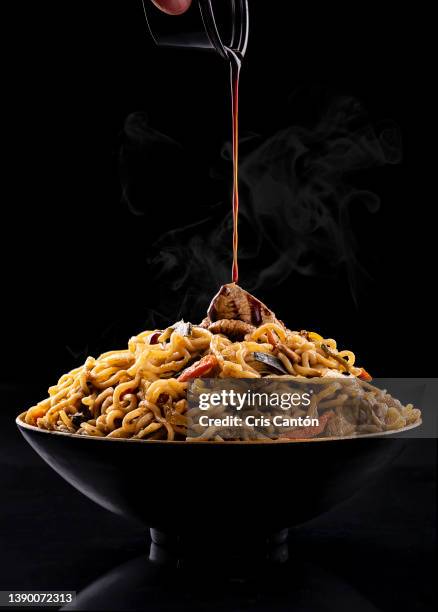 hand pouring soy sauce on bowl of asian noodles - stir frying european stock pictures, royalty-free photos & images