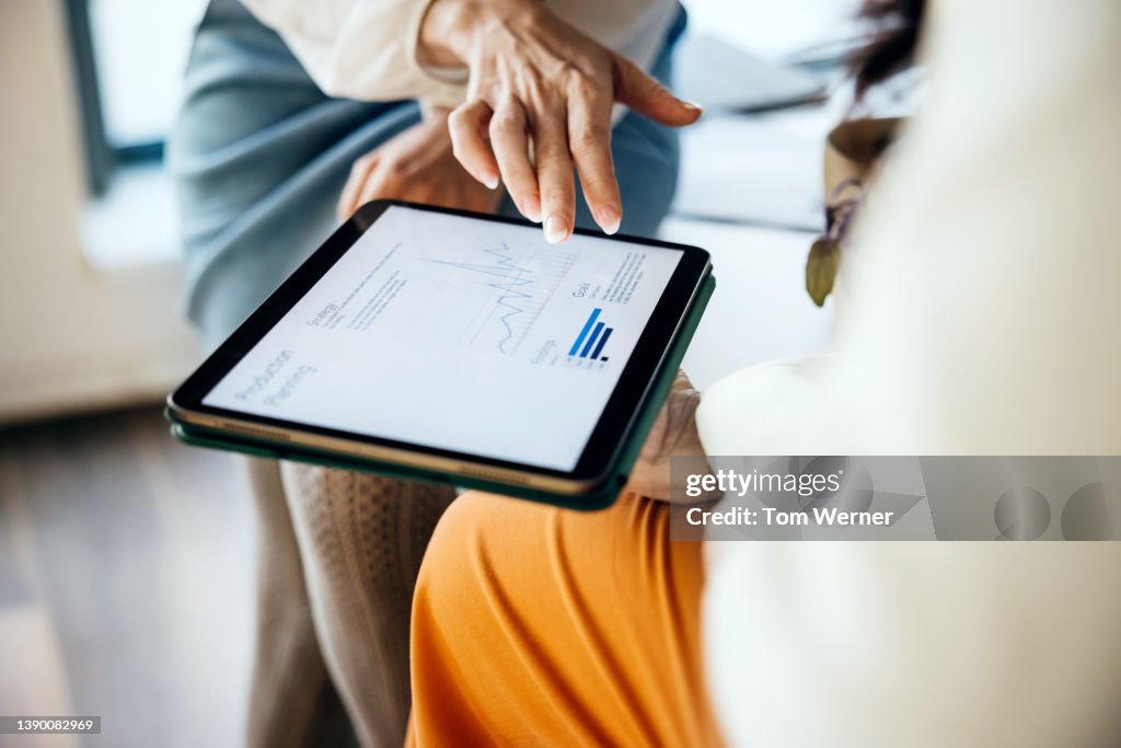 Close Up Of Business Colleagues Using Digital Tablet Together