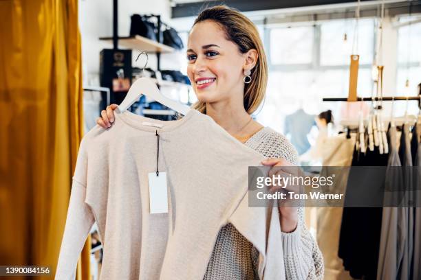 customer looking at pullover while shopping in city - clothing shopping stock pictures, royalty-free photos & images