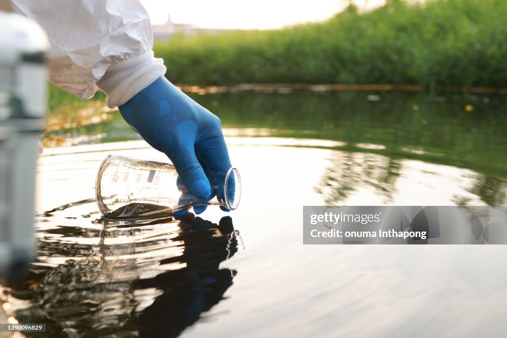 Umweltingenieur Abwasserproben aus Industriekanälen im Reagenzglas sammeln, Hand mit Handschuh Nahaufnahme Abwasserproben aus Industriekanälen im Reagenzglas sammeln. Mobiler Wasserlabor-Check