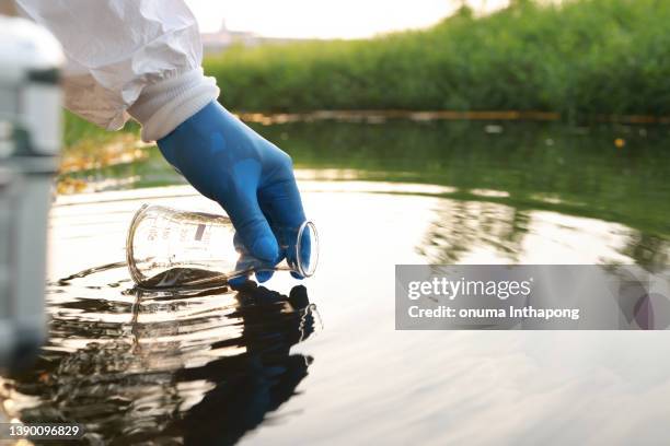 umweltingenieur abwasserproben aus industriekanälen im reagenzglas sammeln, hand mit handschuh nahaufnahme abwasserproben aus industriekanälen im reagenzglas sammeln. mobiler wasserlabor-check - chemikalien stock-fotos und bilder