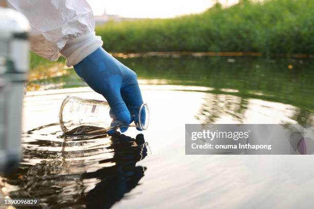environment engineer collect samples of wastewater from industrial canals in test tube, close up hand with glove collect samples of wastewater from industrial canals in test tube. mobile water laboratory check - watervervuiling stockfoto's en -beelden