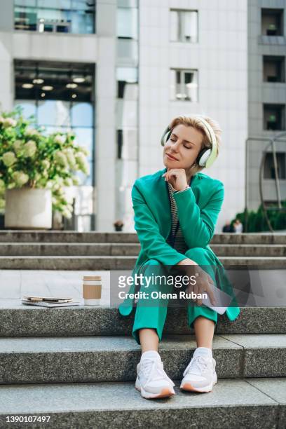 young woman in green suit listening music. - green shoes stock pictures, royalty-free photos & images