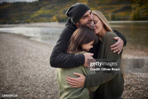 happy family embracing at a riverbank - girl with mother stock-fotos und bilder