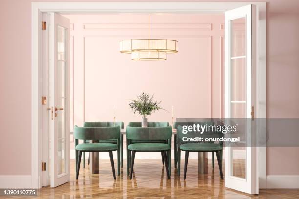 entrance of dining room with dining table, green velvet chairs and pink wall in background - eetkamer stockfoto's en -beelden