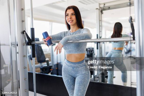 sportliche frau, die energy drink im fitnessstudio trinkt - energydrink stock-fotos und bilder