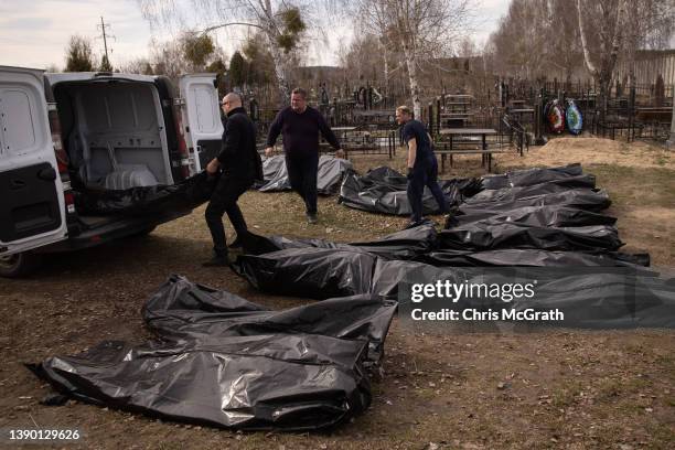 Cemetery workers unload bodies of civilians killed in and around Bucha before they are transported to the morgue at a cemetery on April 07, 2022 in...