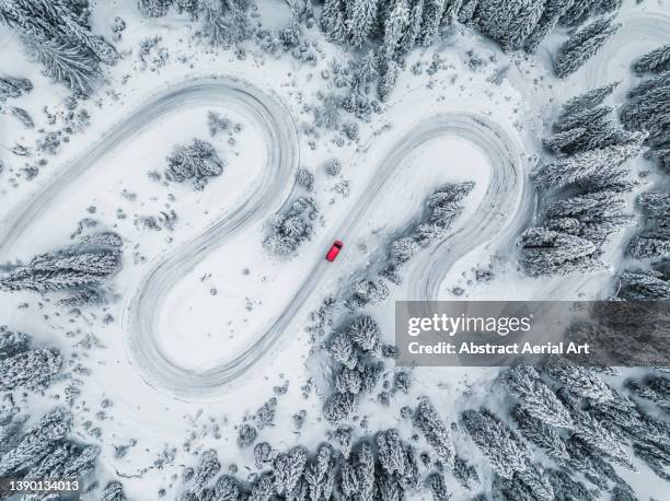 camper van driving on a winding road through a snow covered forest seen from directly above, dolomites, italy - isolated color photos et images de collection