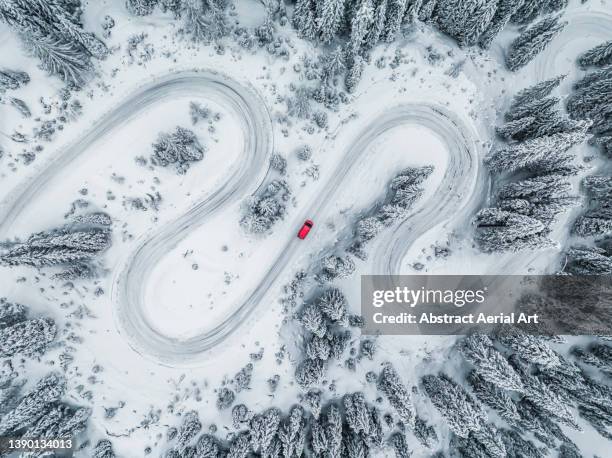 camper van driving on a winding road through a snow covered forest seen from directly above, dolomites, italy - aerial mountain pass imagens e fotografias de stock