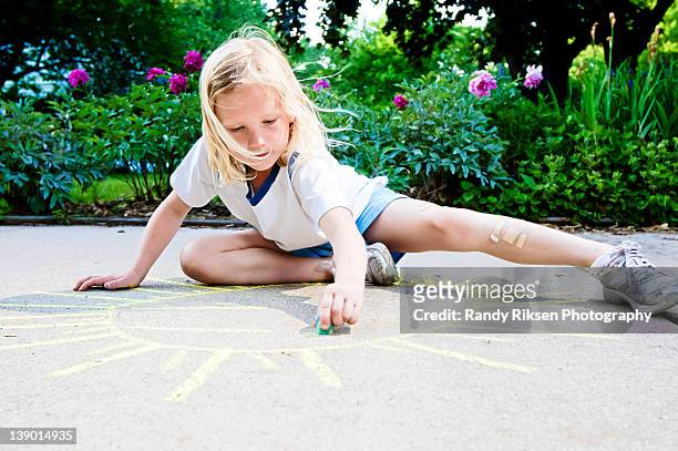 young girl drawing sunshine with sidewalk chalk - sidewalk chalk drawing stock pictures, royalty-free photos & images