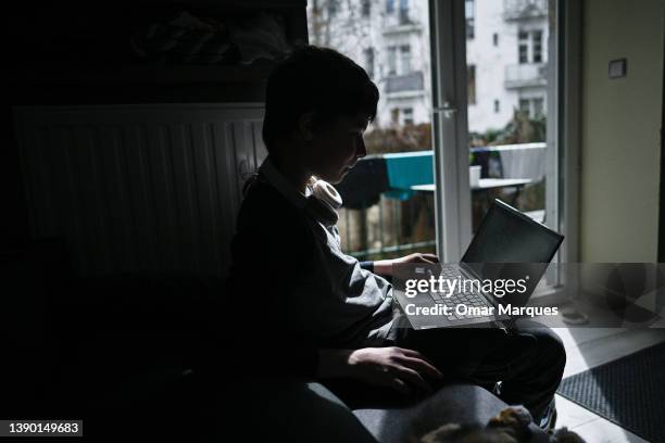 Vasyl, 12 years-old holds a laptop after an online class with his school in Kyiv got cancelled as bombing siren alarm was activated and the teacher...