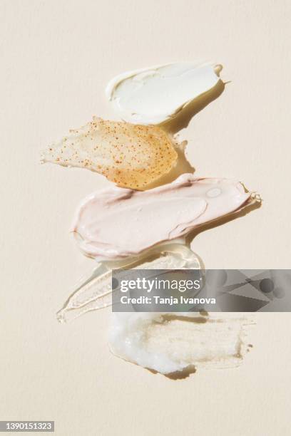 textured multi colored smears of cosmetics on a beige background. samples of creams, face mask, scrub with exfoliating particles, face gel, serum. flat lay, top view. - cosmétique photos et images de collection