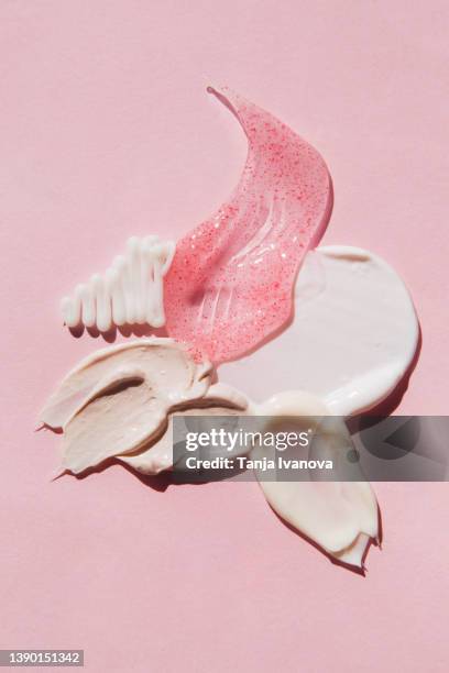 textured multi colored smears of cosmetics on pink background. samples of creams, face mask, scrub with exfoliating particles, face gel, serum. flat lay, top view. - texture maquillage photos et images de collection