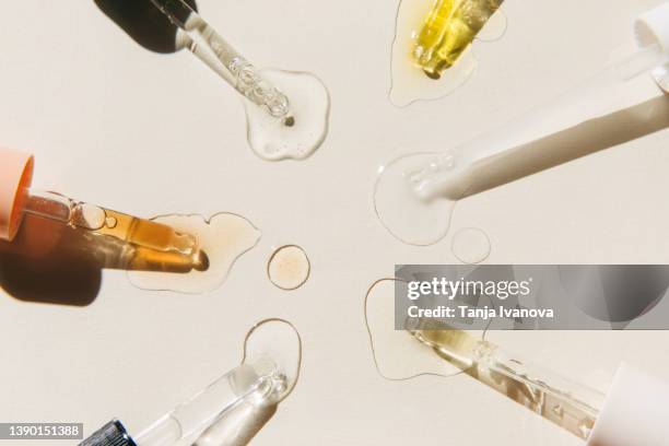 pipettes with drops of cosmetic liquid on beige background. beauty product with peptides, ceramides, hyaluronic gel, polyglutamic acid, essential oil, cbd, retinol, collagen. multitasking beauty. flat lay, top view. - essence stock pictures, royalty-free photos & images