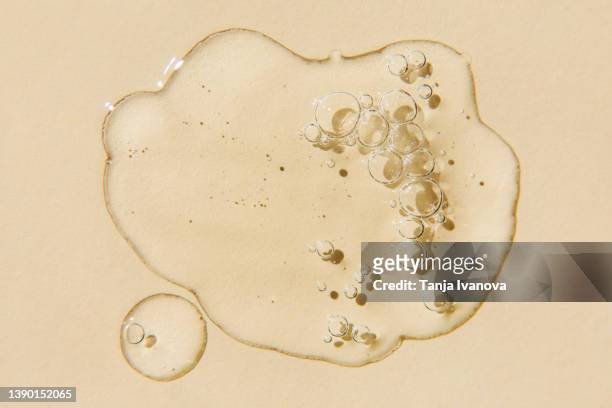 transparent drops of serum on beige background. liquid hyaluronic acid gel. flat lay, top view. - jojoba oil stock pictures, royalty-free photos & images