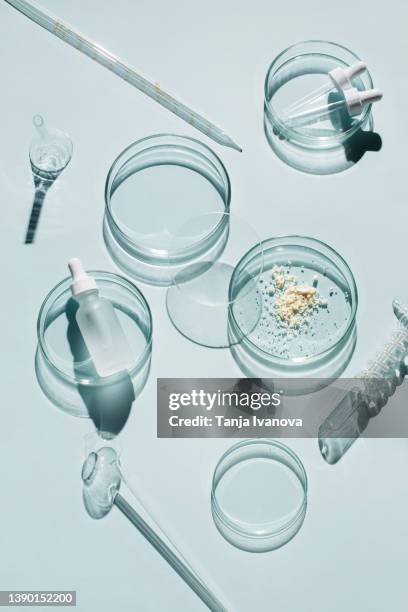 laboratory glassware and cosmetic glass bottle on blue background. natural medicine, cosmetic research, bio science, organic skin care products. top view, flat lay. research and development concept. - laboratory glassware stock-fotos und bilder