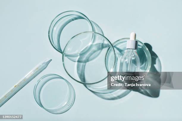 laboratory glassware and cosmetic glass bottle on blue background. natural medicine, cosmetic research, bio science, organic skin care products. top view, flat lay. research and development concept. - laboratoriumglas stockfoto's en -beelden