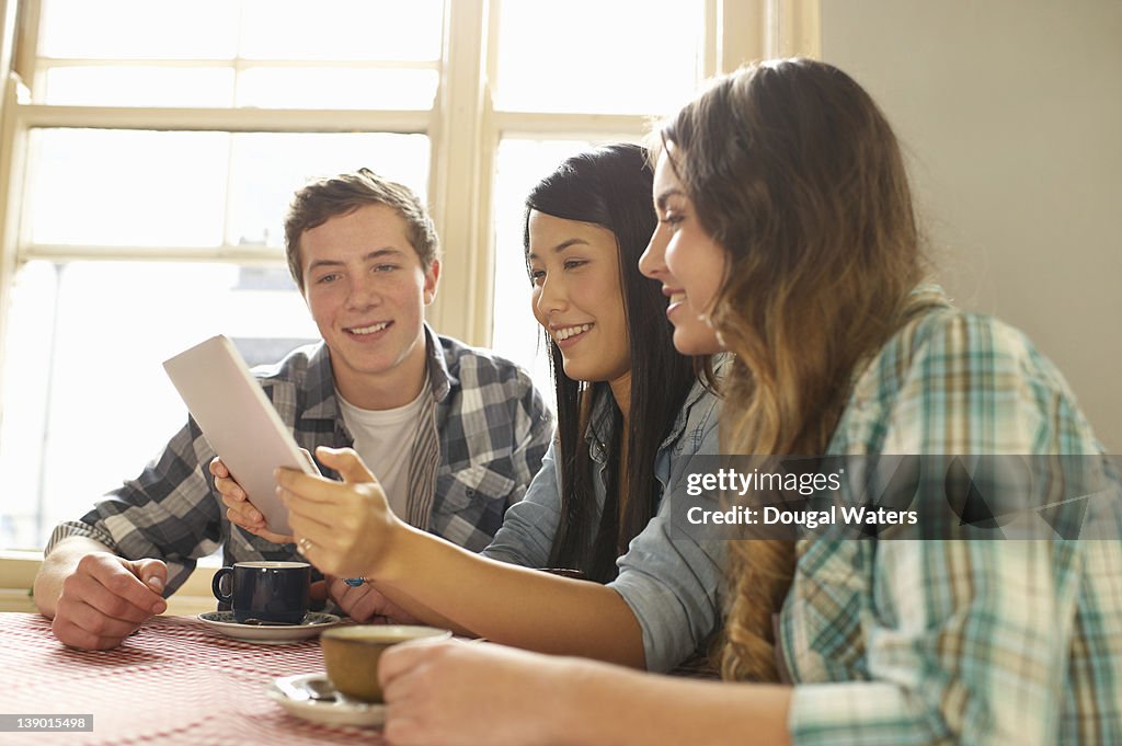 Students using digital tablet in coffee shop.